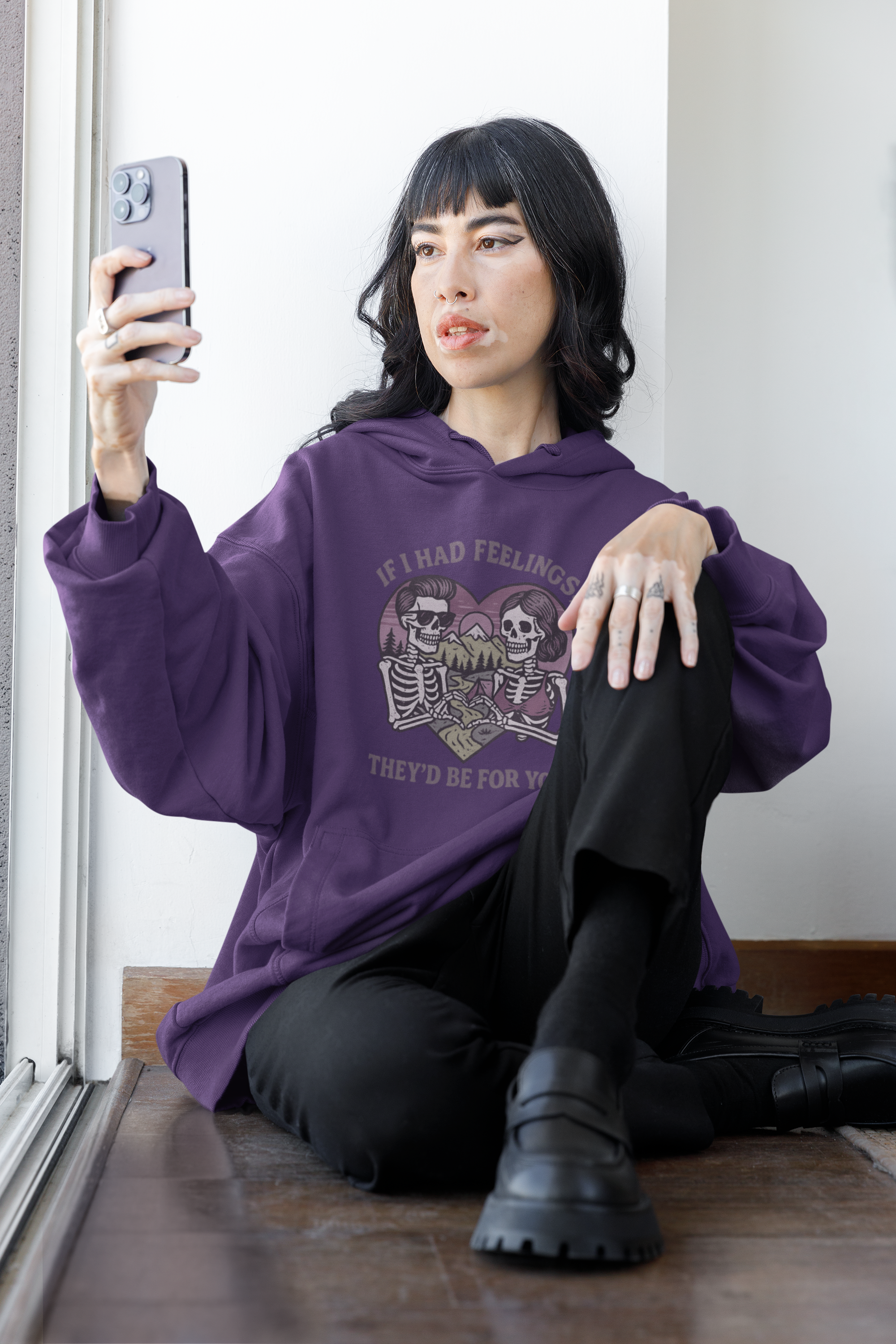 Person wearing Barely Functioning Co. purple hoodie with skeleton graphic and text 'If I Had Feelings, They’d Be For You,' sitting on the floor taking a selfie.